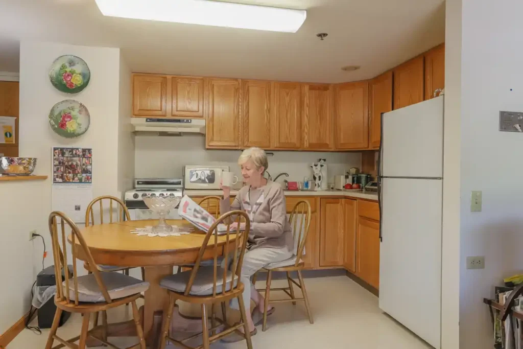 Senior woman enjoying coffee reading the newspaper at her kitchen table