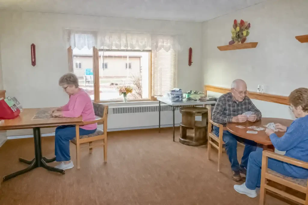 Senior residents playing cards and putting a puzzle together in an activity room